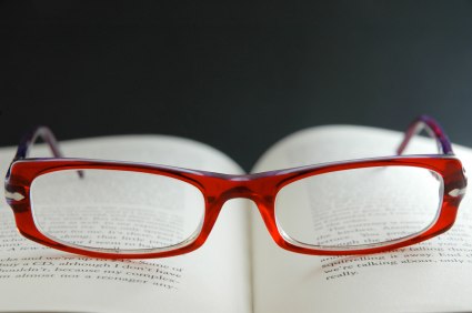A pair of red spectacles on top of an open book